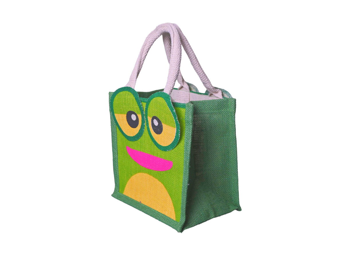 A green jute tote bag featuring a cartoon frog face design with large round eyes, yellow accents, and a pink mouth, complete with cotton cord handles, facing 45 degrees to the left, shown on a plain white background.