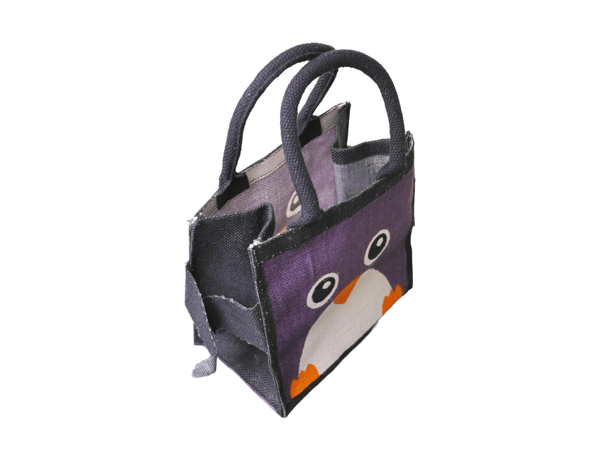 A small black jute tote bag with a purple front panel featuring a cartoon penguin face in white and orange, facing 45 degrees to the left from an angled aerial view, shown on a plain white background.